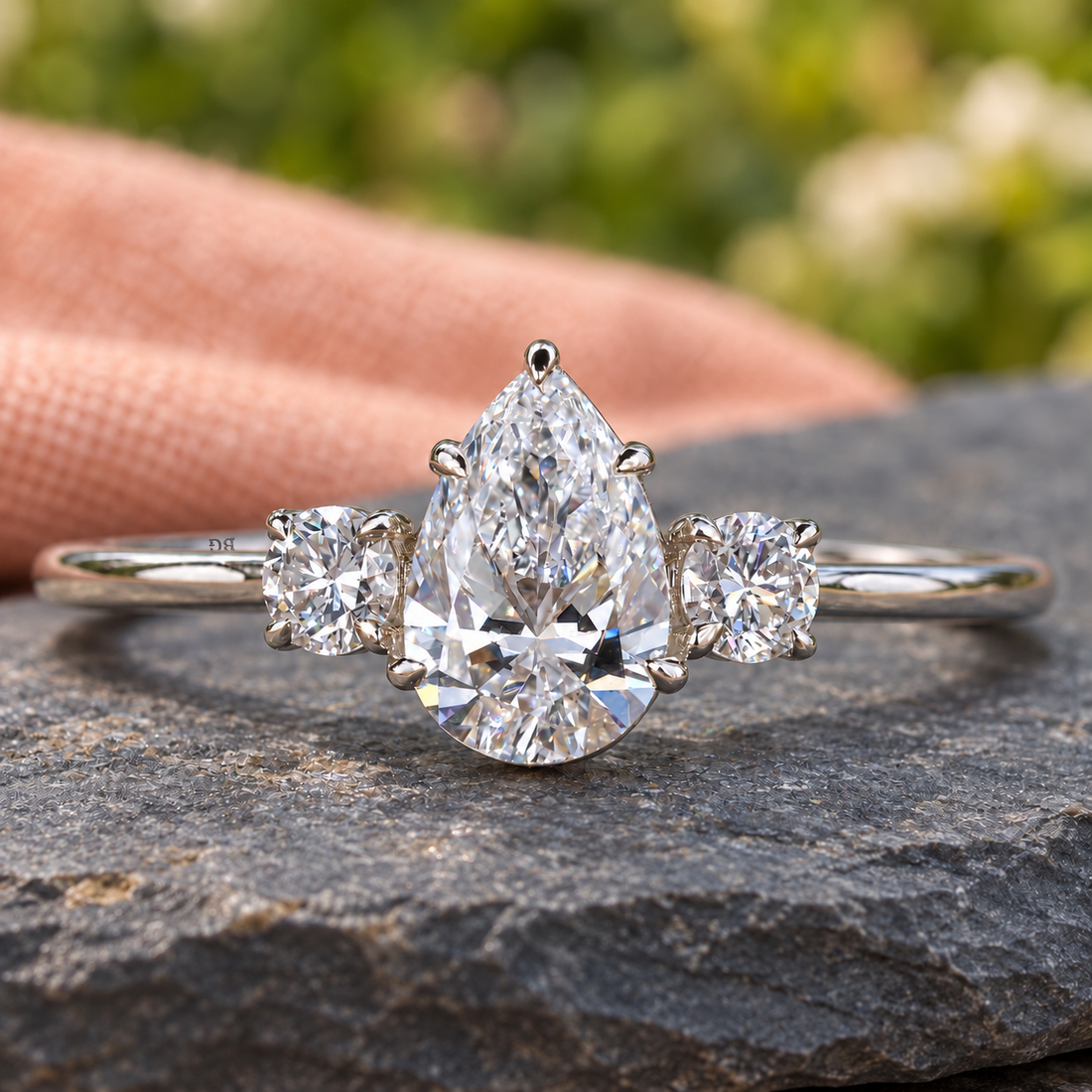 Pear and round three stone lab grown diamond engagement ring in white metal