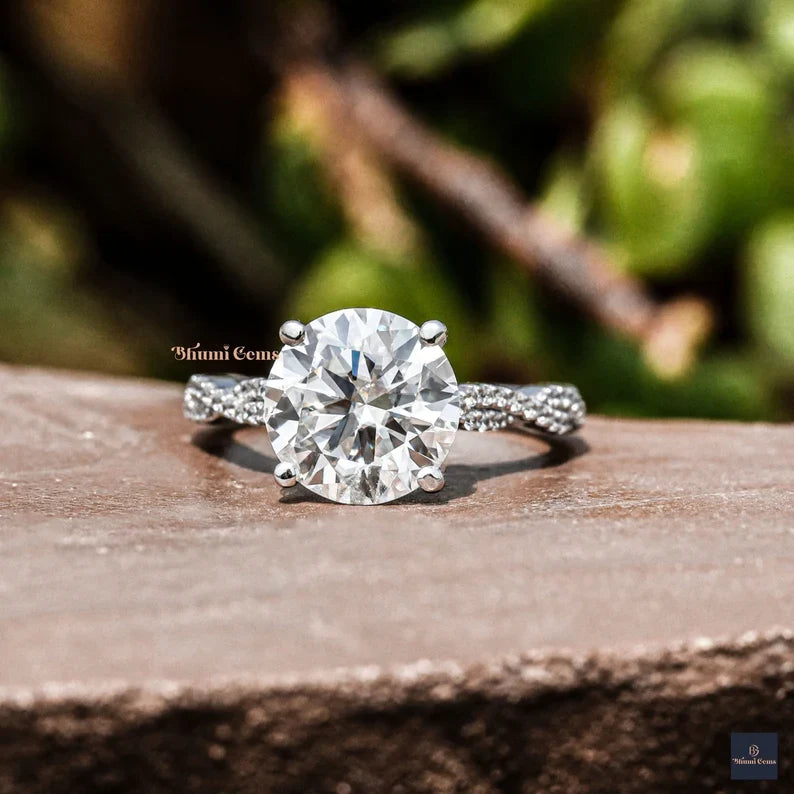 Round moissanite solitaire engagement ring on a twisted pave band in white gold