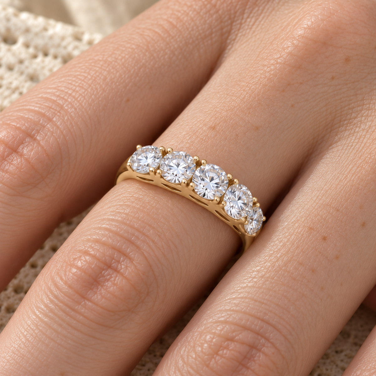 Five stone round moissanite ring in yellow gold worn on the hand