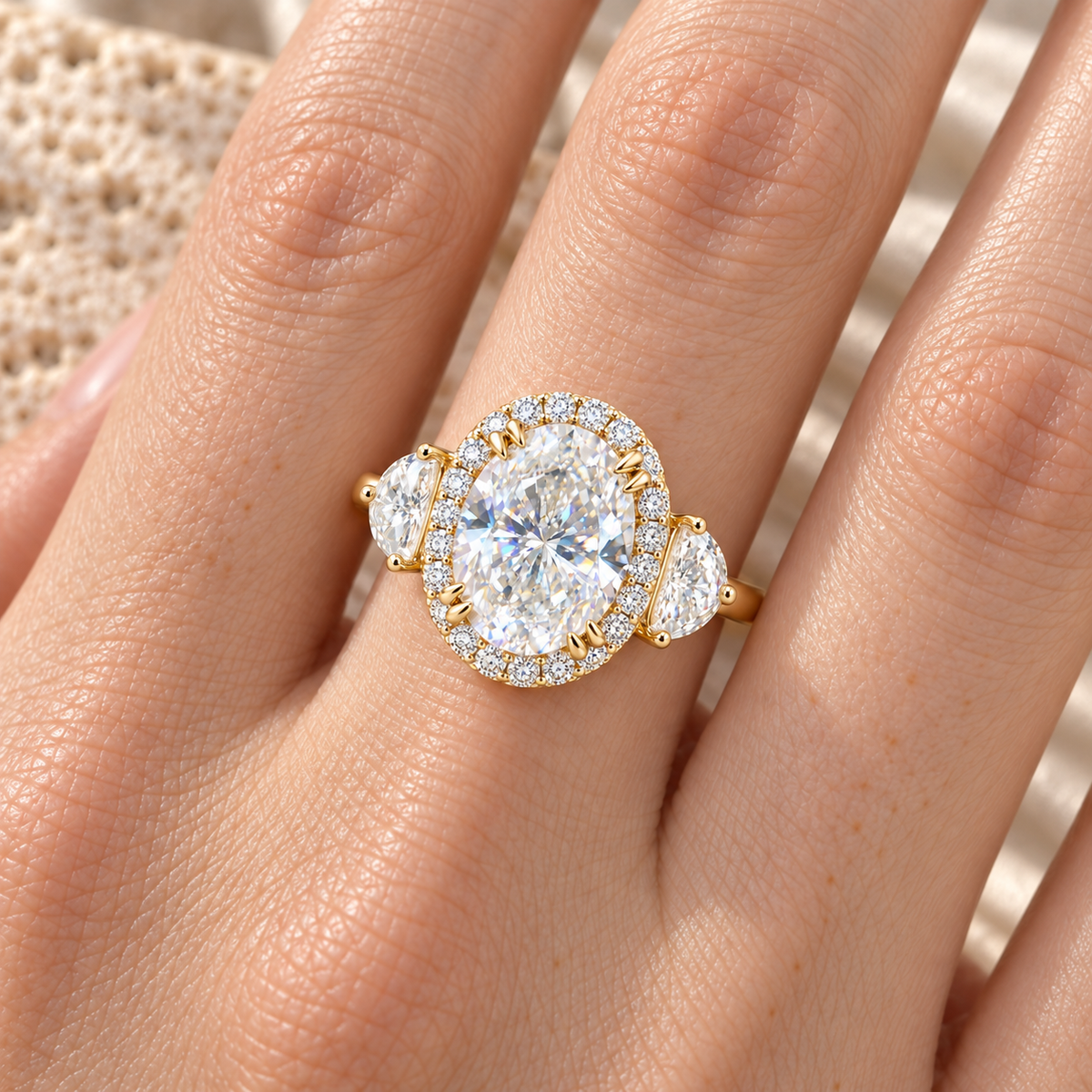 Oval half-moon three-stone moissanite halo ring worn on hand, yellow gold