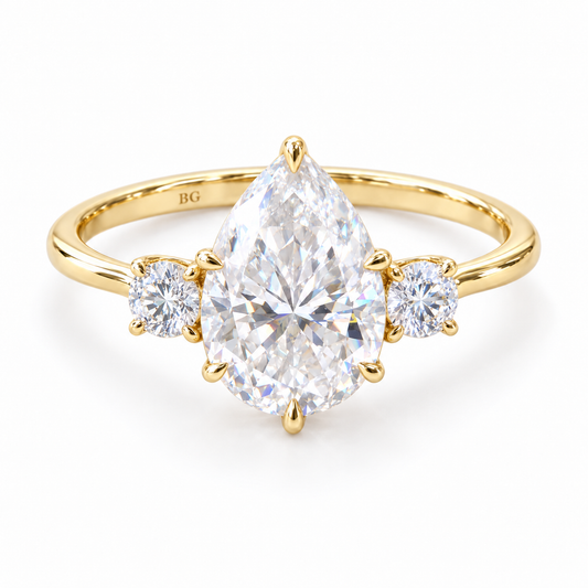 Pear moissanite three stone engagement ring with round side stones in yellow gold