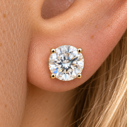 Round moissanite four prong stud earring in yellow gold worn on the ear