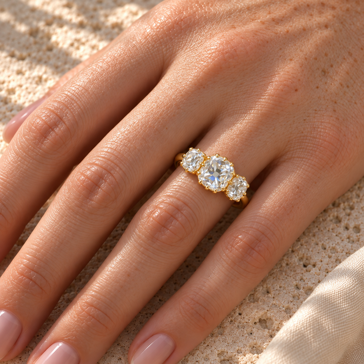Old mine cushion three stone moissanite ring in yellow gold worn on the hand