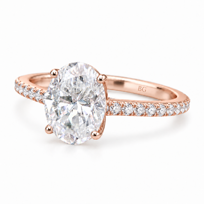 Oval moissanite engagement ring with four prongs and pave band in rose gold