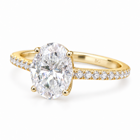 Oval moissanite engagement ring with four prongs and pave band in yellow gold